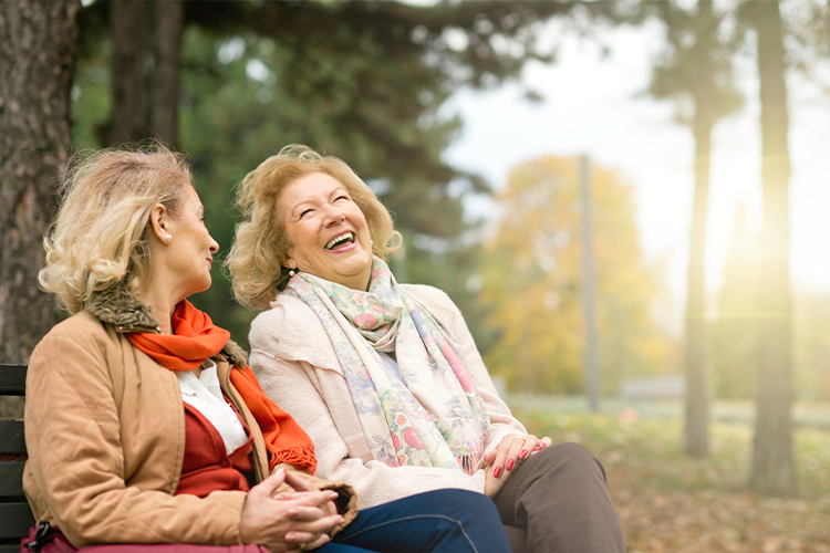 Two women sitting on a park bench in the fall